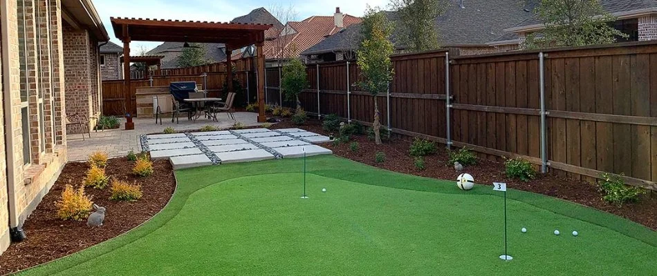 Backyard in Allen, TX with manicured landscape beds and a putting green.